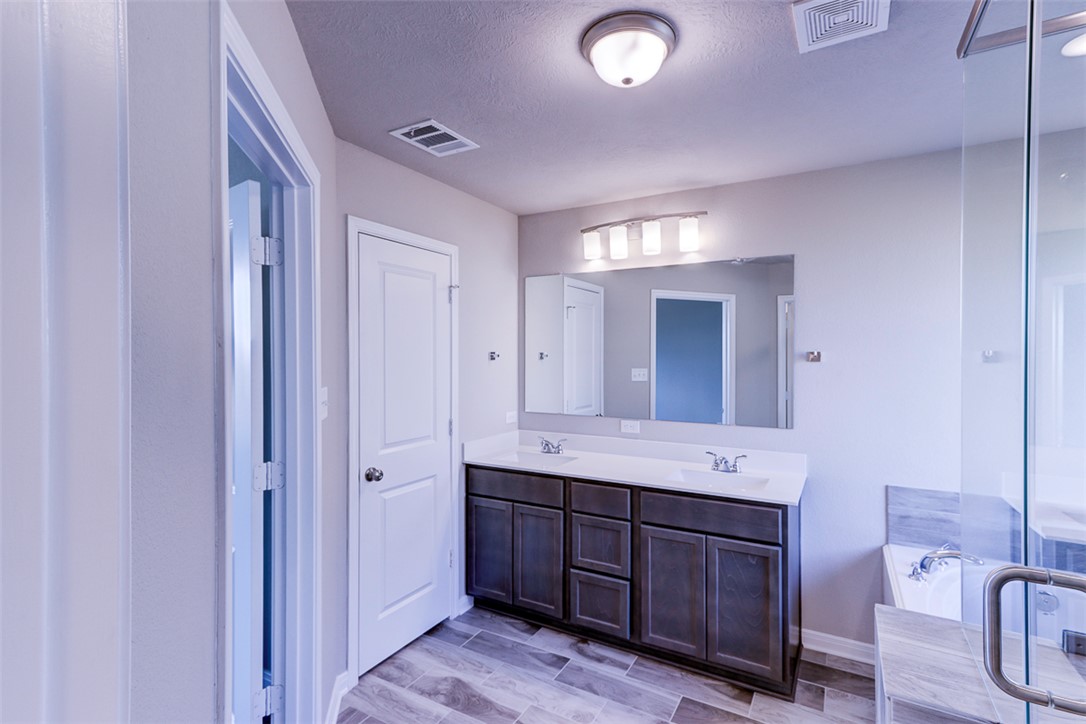 1937 Viva Road Bryan, TX 77807 - Photo 9 of 25 a spacious bathroom with a double vanity sink a mirror and a bathtub