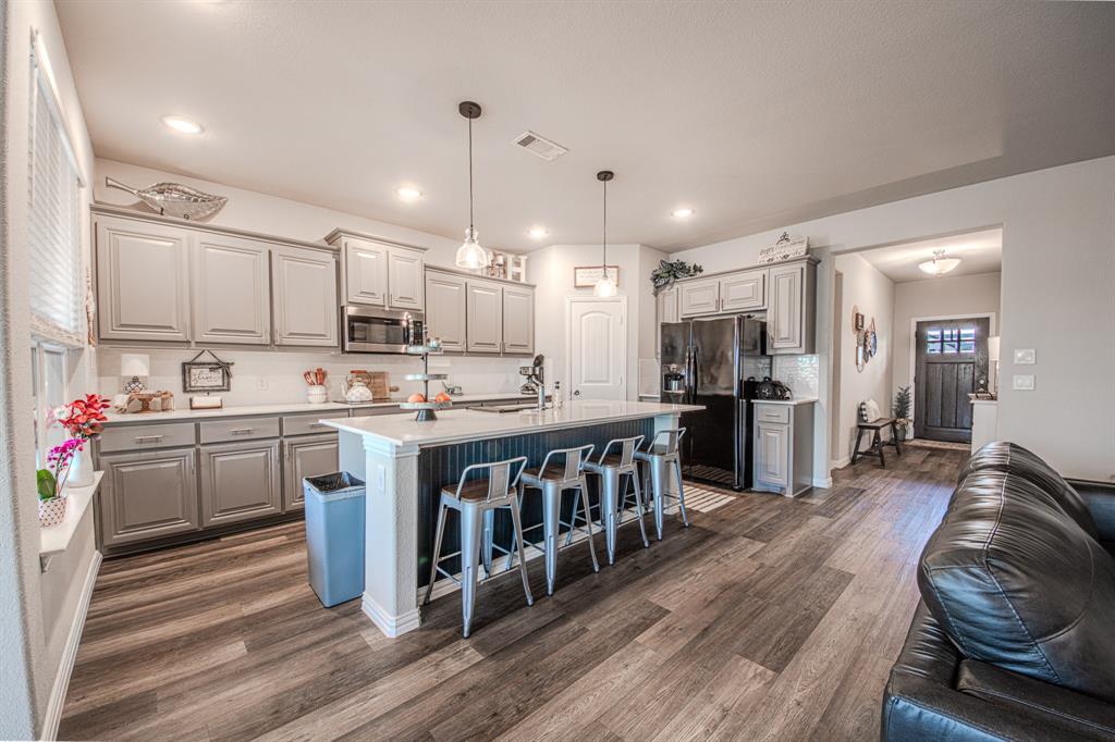 150 Oak Grove Drive Rhome, TX 76078 - Photo 11 of 40 a kitchen with stainless steel appliances kitchen island granite countertop a table chairs refrigerator and a sink