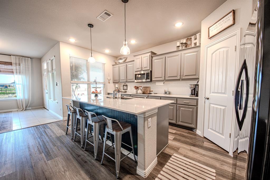 150 Oak Grove Drive Rhome, TX 76078 - Photo 14 of 40 a kitchen with stainless steel appliances granite countertop a refrigerator a sink dishwasher a stove and white countertops with wooden floor