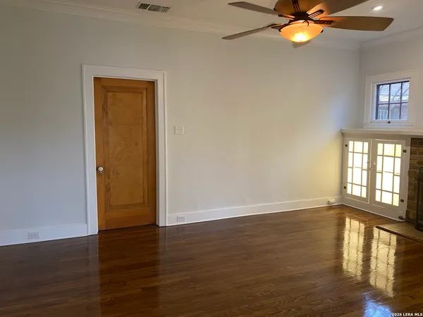 a view of an empty room with wooden floor and a window