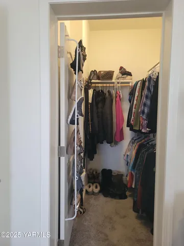 a view of walk in closet with clothes and shoes