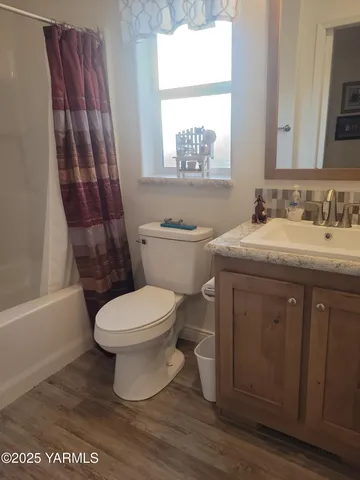 a bathroom with a toilet a sink a mirror a window and vanity