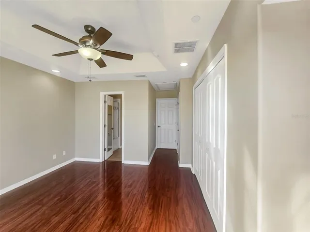a view of a hallway with wooden floor and a ceiling fan