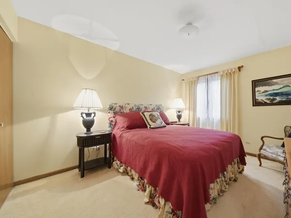 a spacious bedroom with a bed table and a window