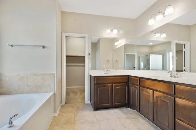 a spacious bathroom with a tub sink and mirror