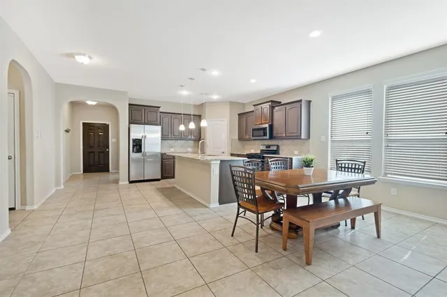 a kitchen with stainless steel appliances kitchen island granite countertop a dining table chairs and granite counter tops