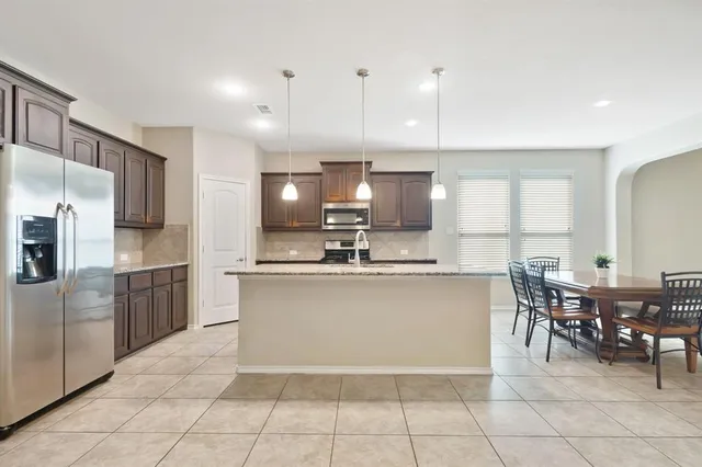 a large kitchen with cabinets chairs and refrigerator