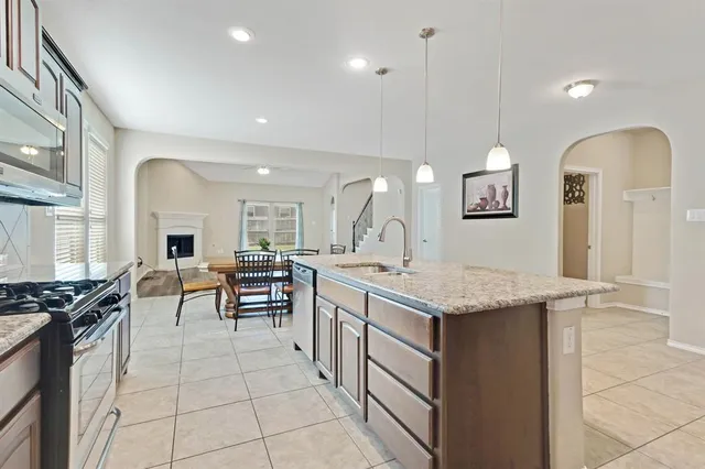 a kitchen with granite countertop a stove a sink a dining table and chairs