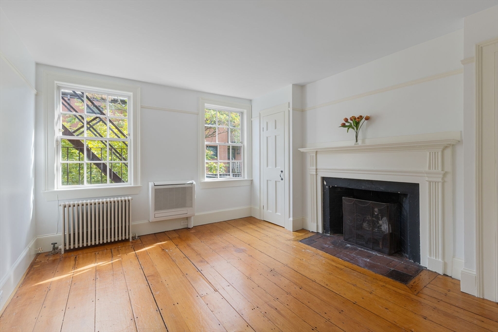 24 Fayette Street, Unit 24 Boston, MA 02116 - Photo 16 of 36 an empty room with windows a fireplace and wooden floor