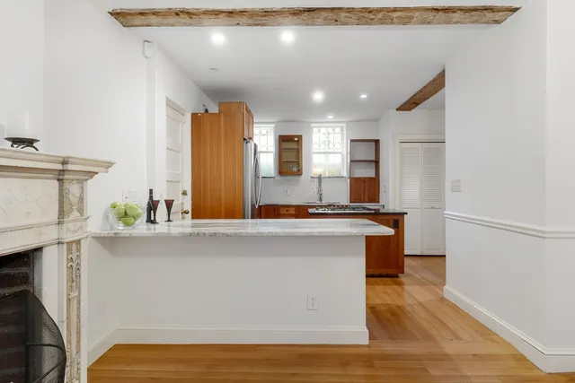 a living room with stainless steel appliances furniture a refrigerator and a kitchen counter top