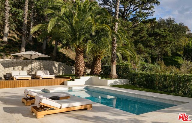 a view of backyard with swimming pool and seating space