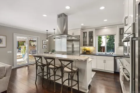 a kitchen with stainless steel appliances granite countertop wooden floor window and wooden cabinets