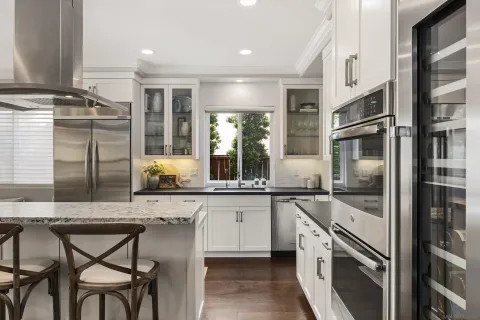 a kitchen with stainless steel appliances granite countertop a stove and chairs