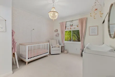 a bedroom with a baby bed a chandelier and a window