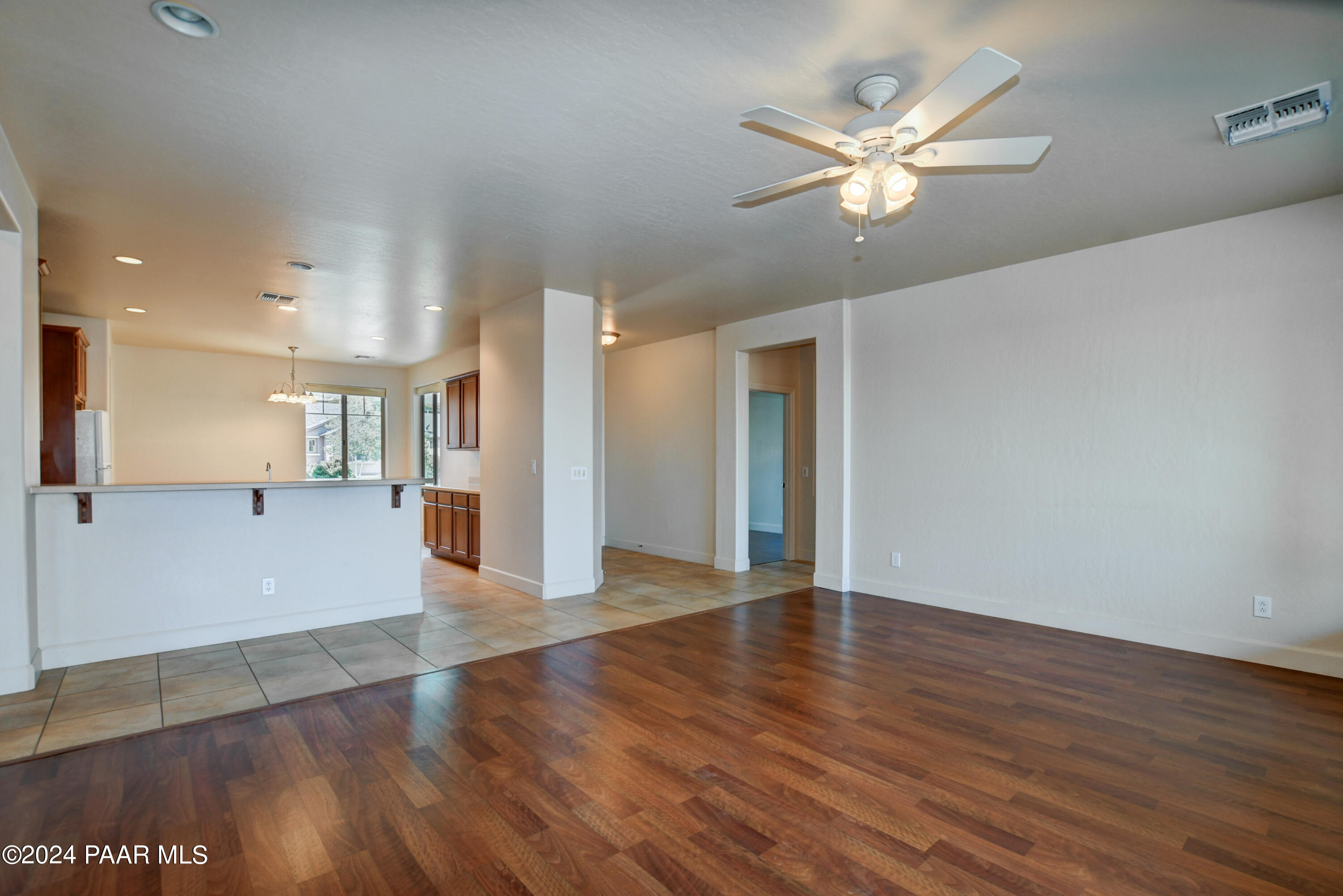 1147 Rusty Nail Road Prescott Valley, AZ 86314 - Photo 7 of 50 a view of an empty room with wooden floor and a ceiling fan