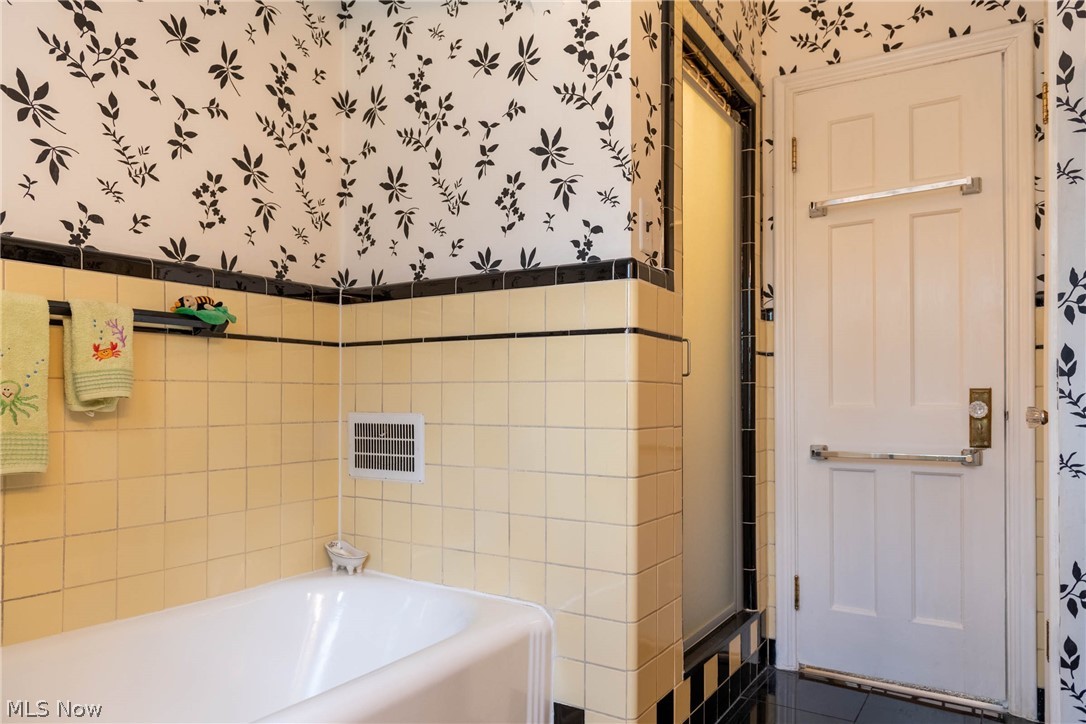 3433 Bradford Road Cleveland, OH 44118 - Photo 20 of 35 The yellow & black tiles around the the Tub, Shower & flr, create a fun Art Deco effect. The Door in the middle is the shower stall, while the white dr ahead leads out into the hallway.