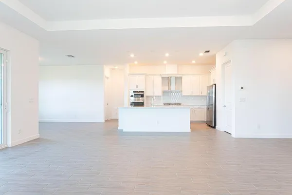 a view of kitchen with kitchen island a sink wooden floor and a refrigerator
