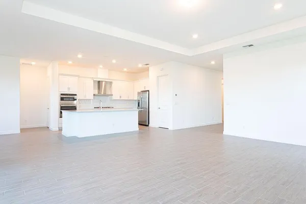 a view of a kitchen with kitchen island a sink wooden floor and a large window