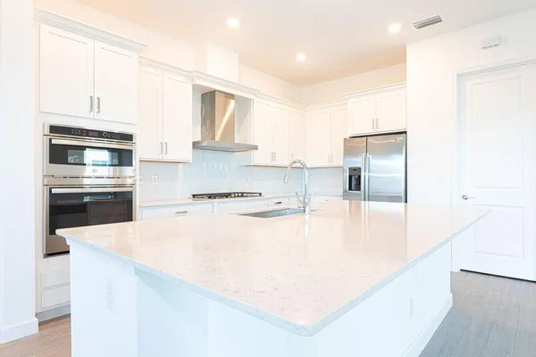 a kitchen with stainless steel appliances granite countertop a sink and white cabinets with wooden floor