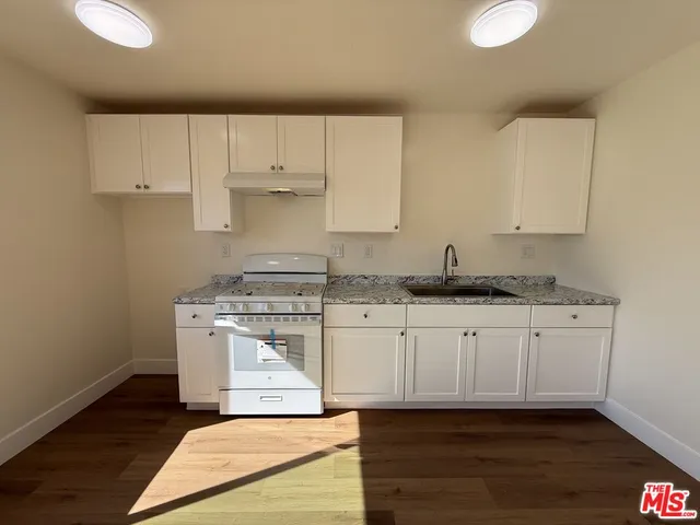 a kitchen with granite countertop white cabinets and white appliances