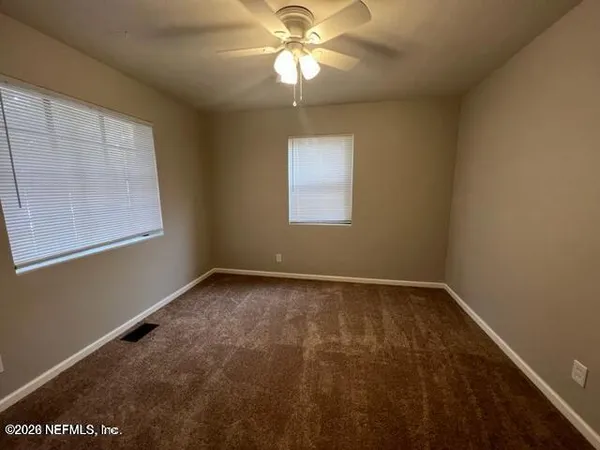 an empty room with a window and a chandelier fan