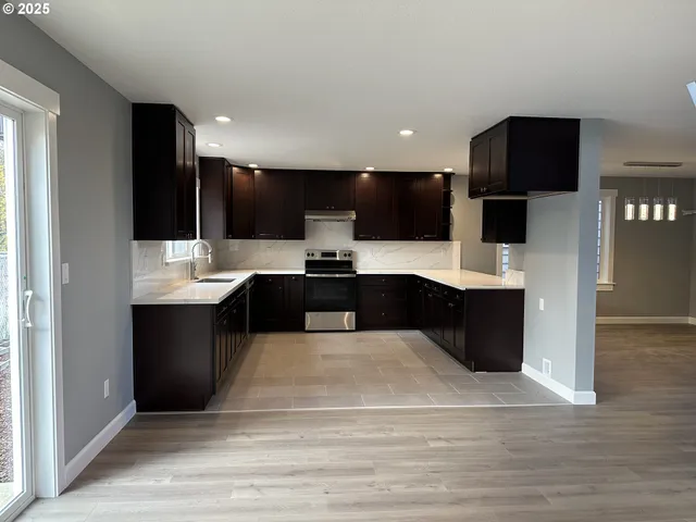 a large kitchen with stainless steel appliances kitchen island granite countertop a large counter top a stove and a refrigerator