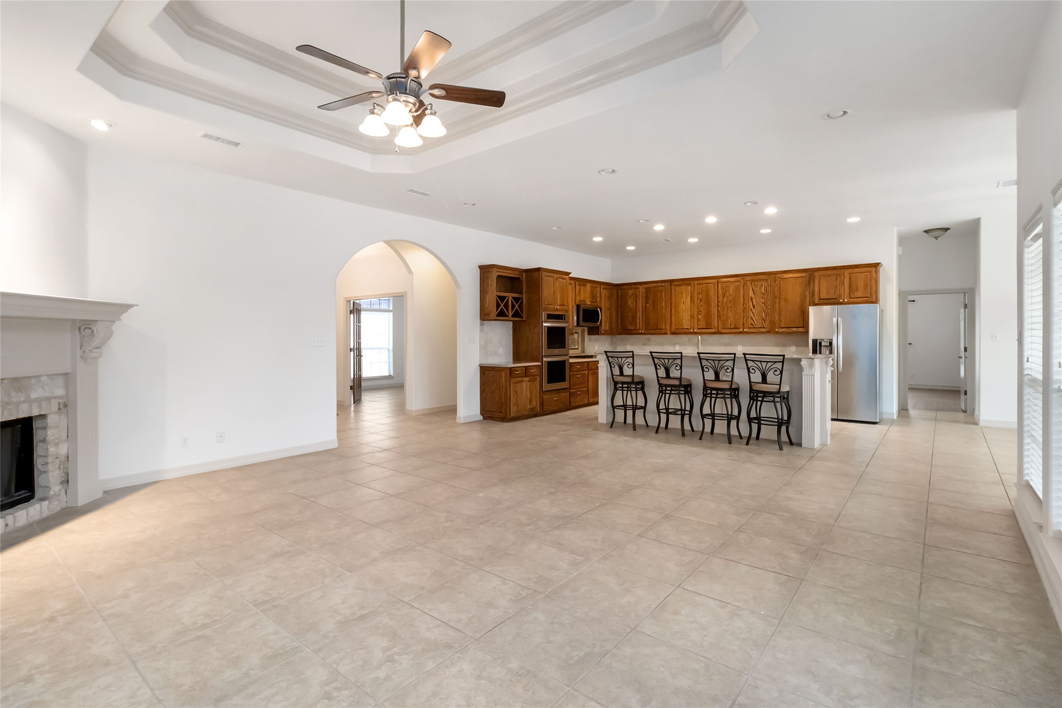 167 Winchester Road Bastrop, TX 78602 - Photo 12 of 34 Kitchen with brown cabinetry, arched walkways, light countertops, a breakfast bar area, and recessed lighting