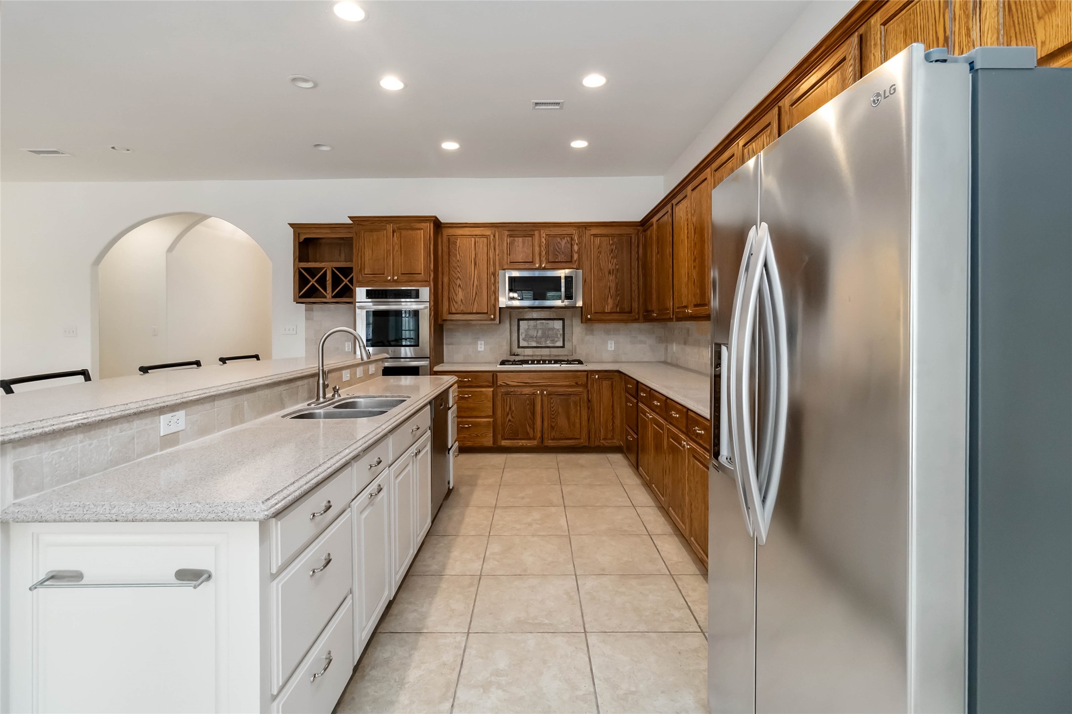 167 Winchester Road Bastrop, TX 78602 - Photo 14 of 34 Kitchen with stainless steel appliances, recessed lighting, brown cabinets, backsplash, and light tile patterned flooring