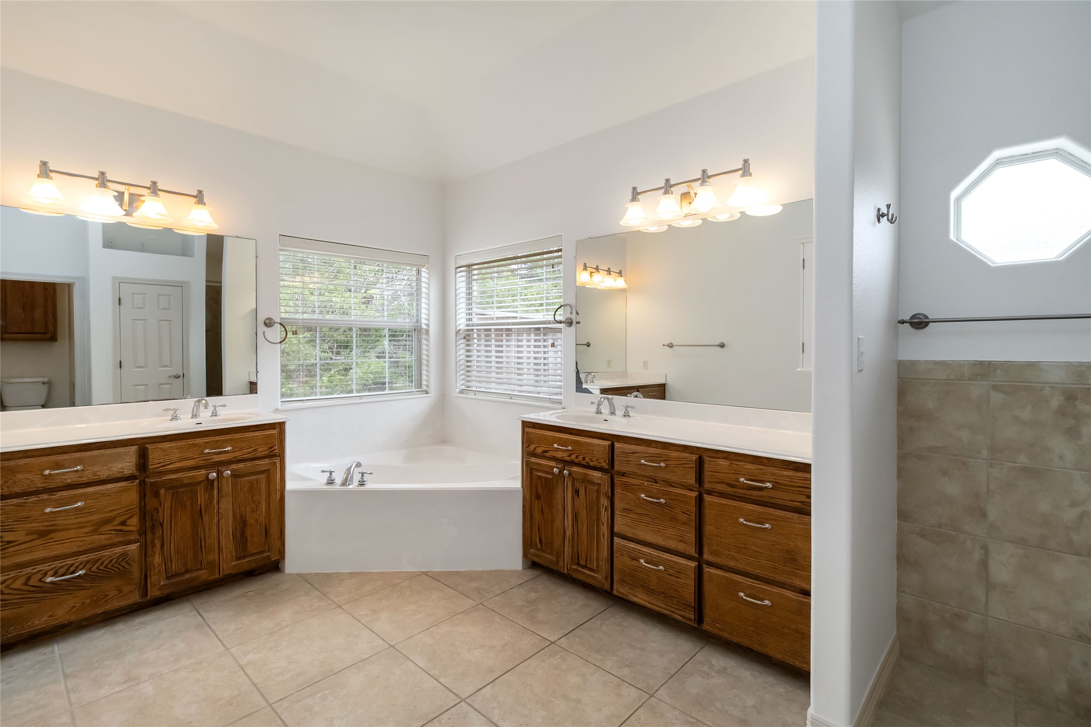 167 Winchester Road Bastrop, TX 78602 - Photo 21 of 34 Bathroom featuring healthy amount of natural light, two vanities, light tile patterned floors, and a garden tub