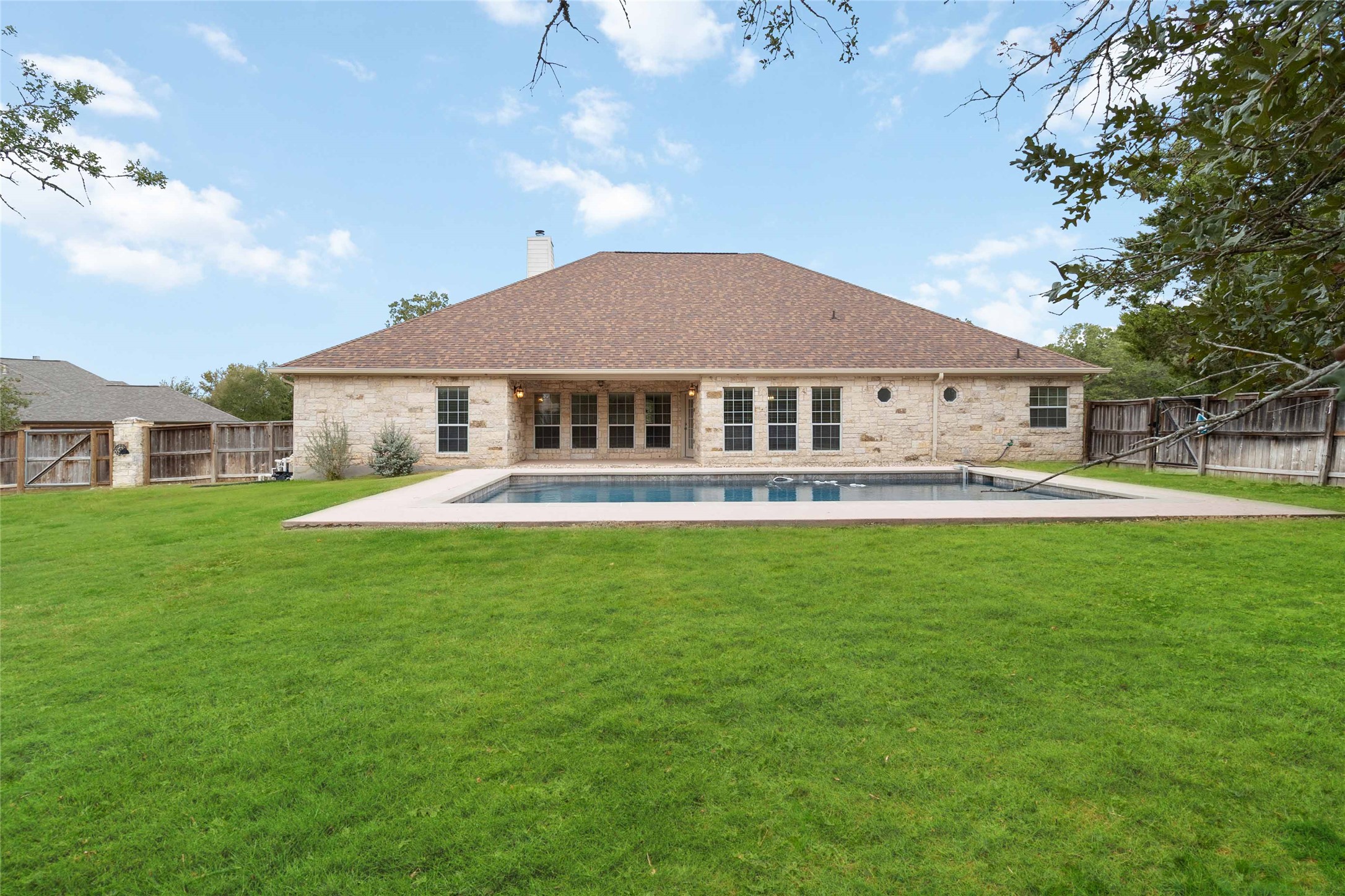167 Winchester Road Bastrop, TX 78602 - Photo 31 of 34 Rear view of property with a patio, a fenced backyard, a chimney, and a gate