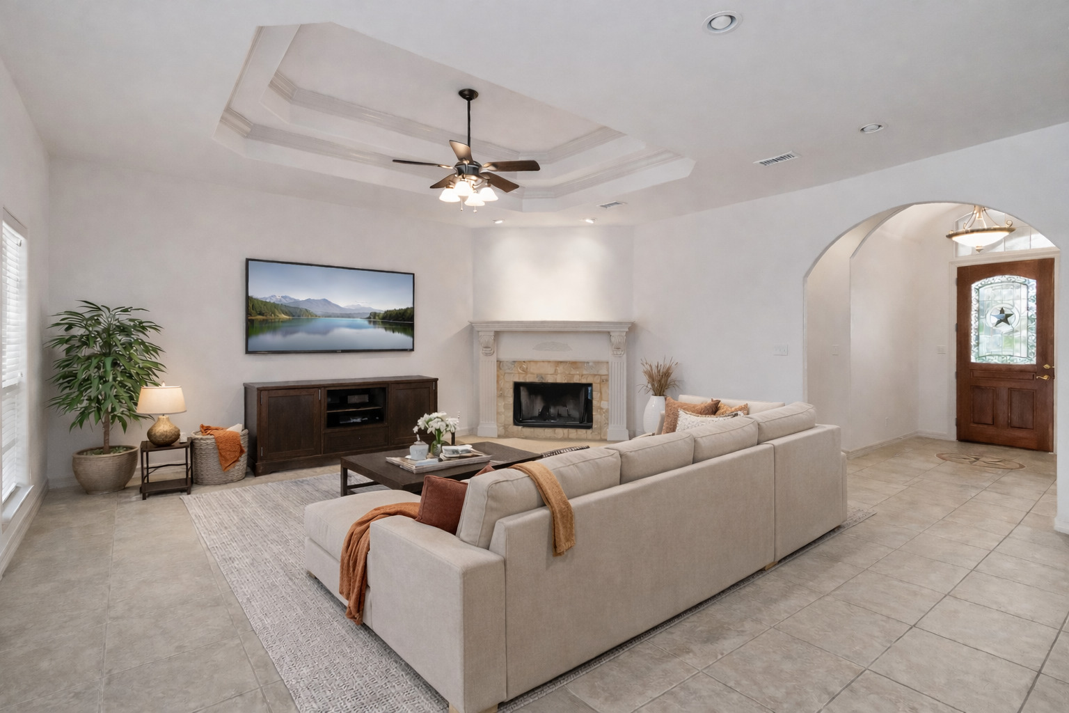 167 Winchester Road Bastrop, TX 78602 - Photo 4 of 34 Living area with a tiled fireplace, ceiling fan, a tray ceiling, and arched walkways