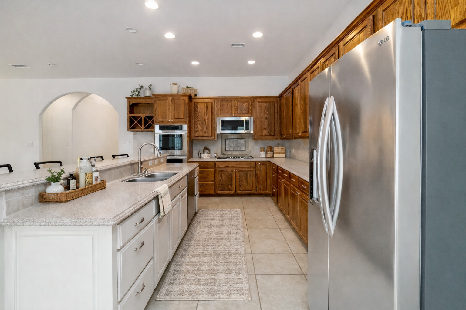 167 Winchester Road Bastrop, TX 78602 - Photo 6 of 34 Kitchen featuring stainless steel appliances, recessed lighting, brown cabinets, light tile patterned flooring, and light stone countertops