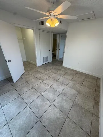 a view of an empty room with fan and window