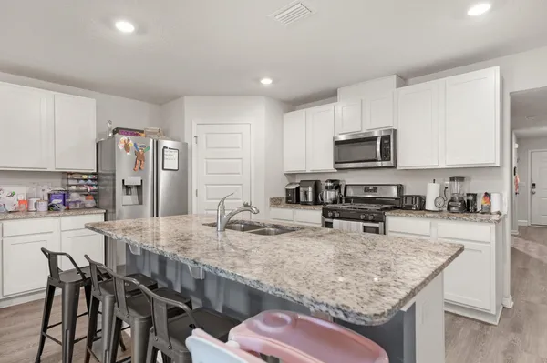a kitchen with stainless steel appliances granite countertop a sink dishwasher a stove refrigerator and microwave with wooden floor