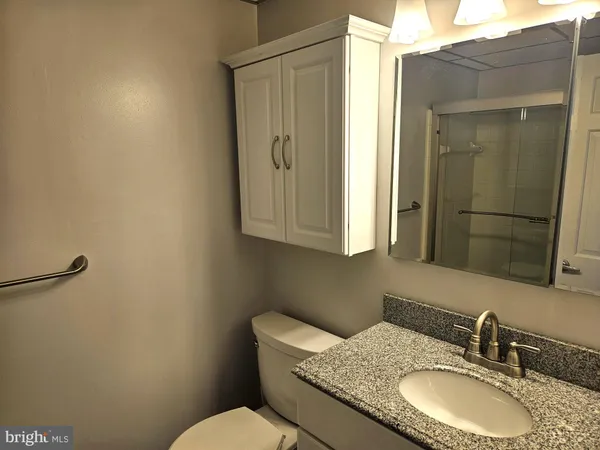 a bathroom with a granite countertop sink a mirror and a toilet