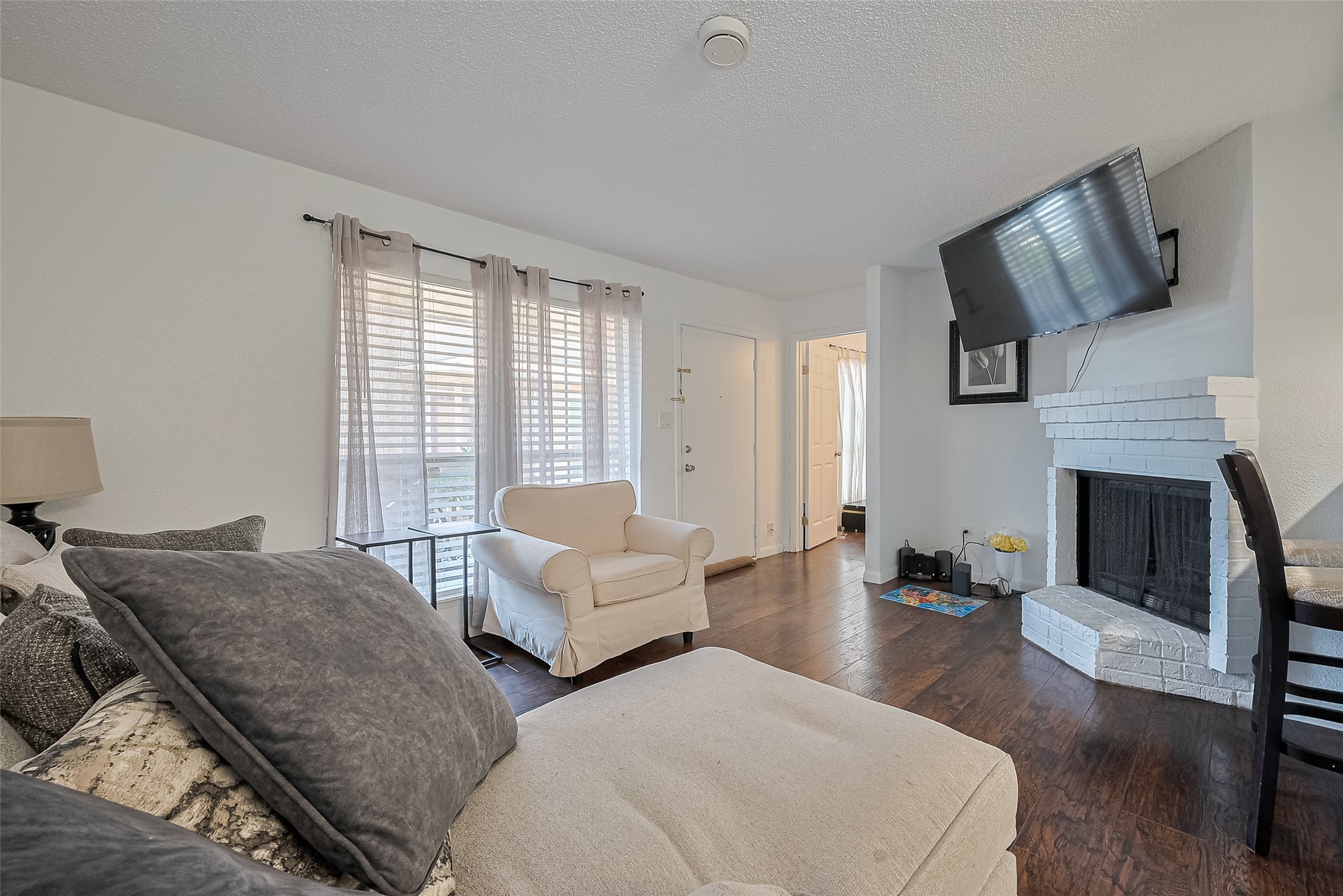 1505 Ward Road, Unit 118 Baytown, TX 77520 - Photo 8 of 35 Bright living room with hardwood floors, neutral walls, and ample natural light from a large window. Features a cozy seating area with a sofa and armchair, creating a welcoming atmosphere.