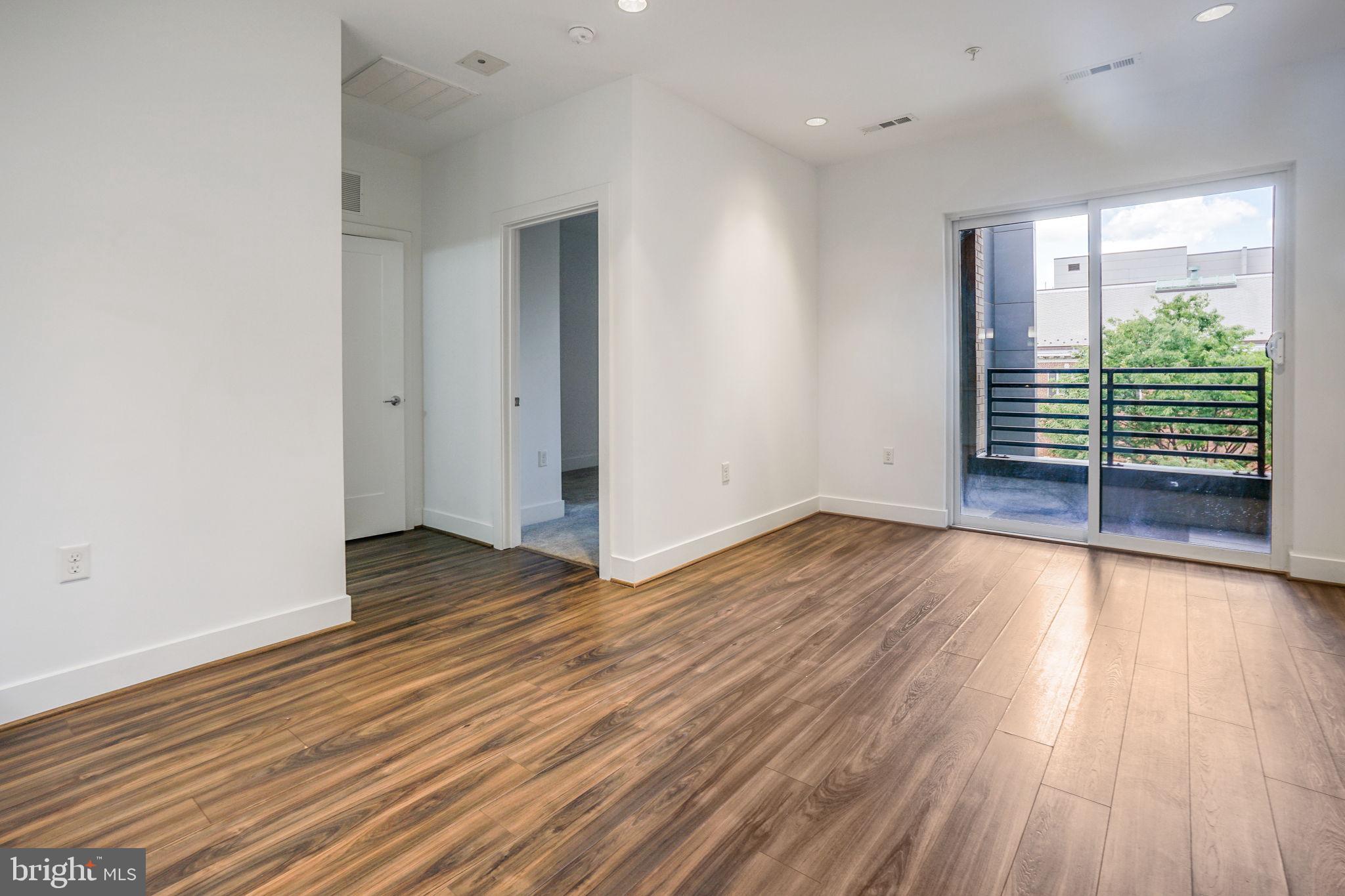 1111 Orren Street Northeast, Unit 310 Washington, DC 20002 - Photo 3 of 26 an empty room with wooden floor and windows