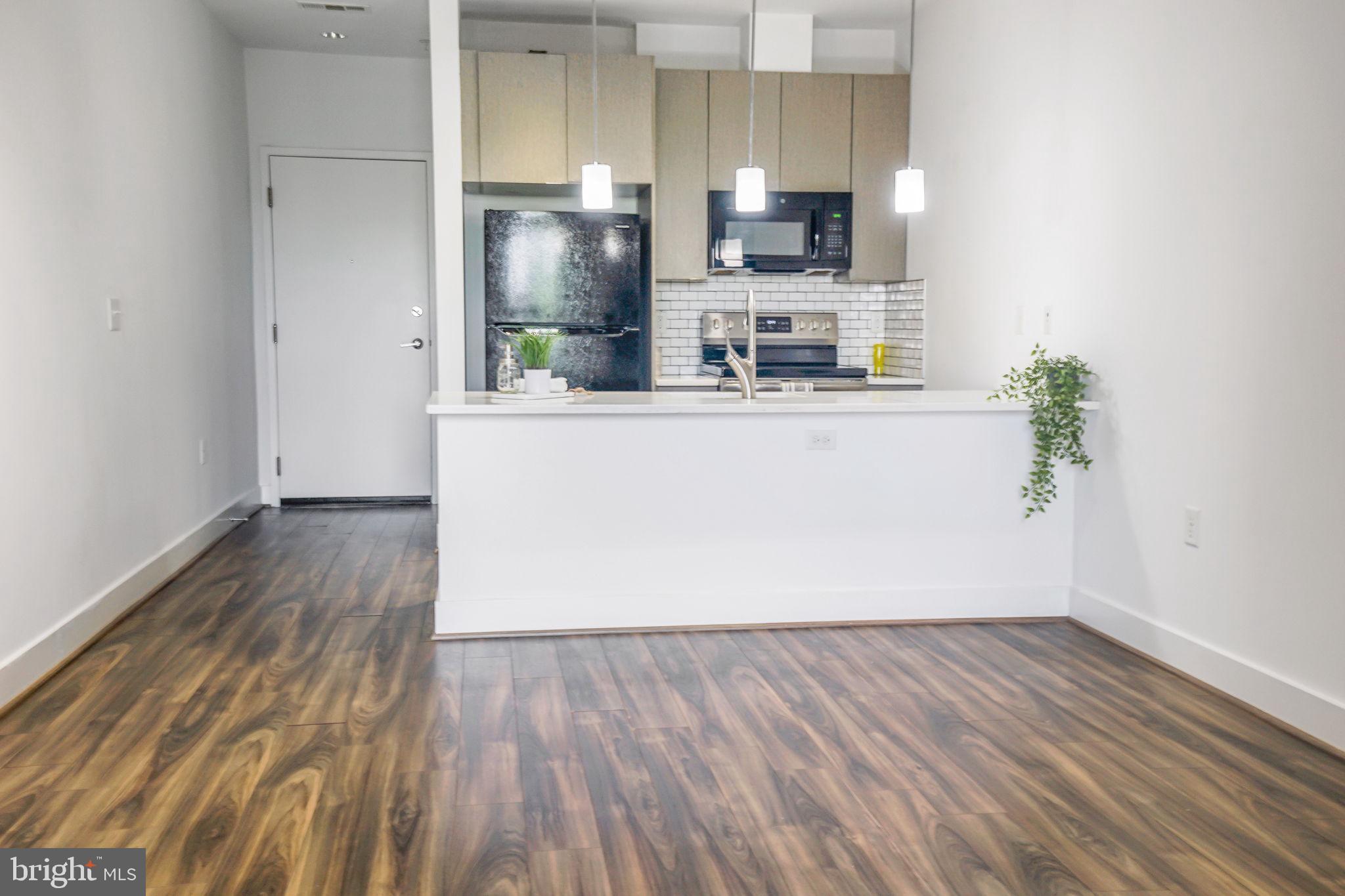 1111 Orren Street Northeast, Unit 310 Washington, DC 20002 - Photo 5 of 26 a room with wooden floor and cabinets