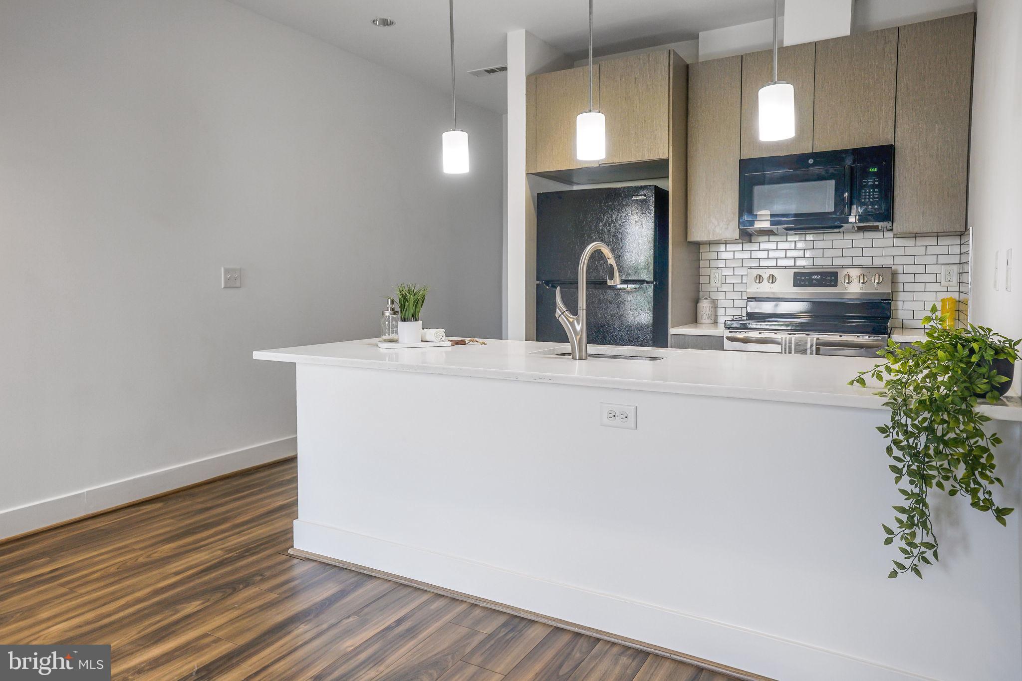 1111 Orren Street Northeast, Unit 310 Washington, DC 20002 - Photo 8 of 26 a room with kitchen island a sink wooden floor and a fireplace