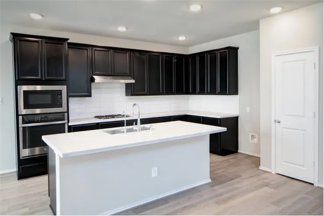 a kitchen with kitchen island a sink stainless steel appliances and cabinets
