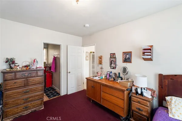 a bedroom with a bed next to a window with on the dresser and a window