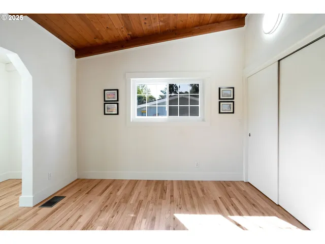 a view of an empty room with wooden floor and windows