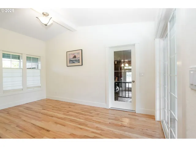 a view of an empty room with window and wooden floor