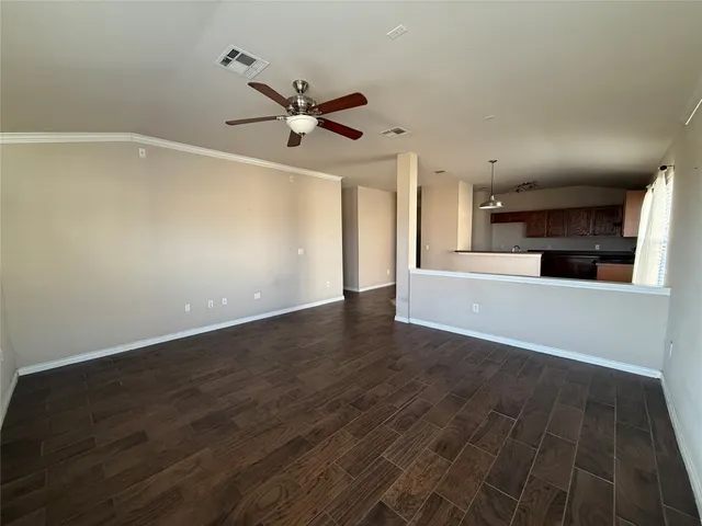 an empty room with wooden floor fan and windows