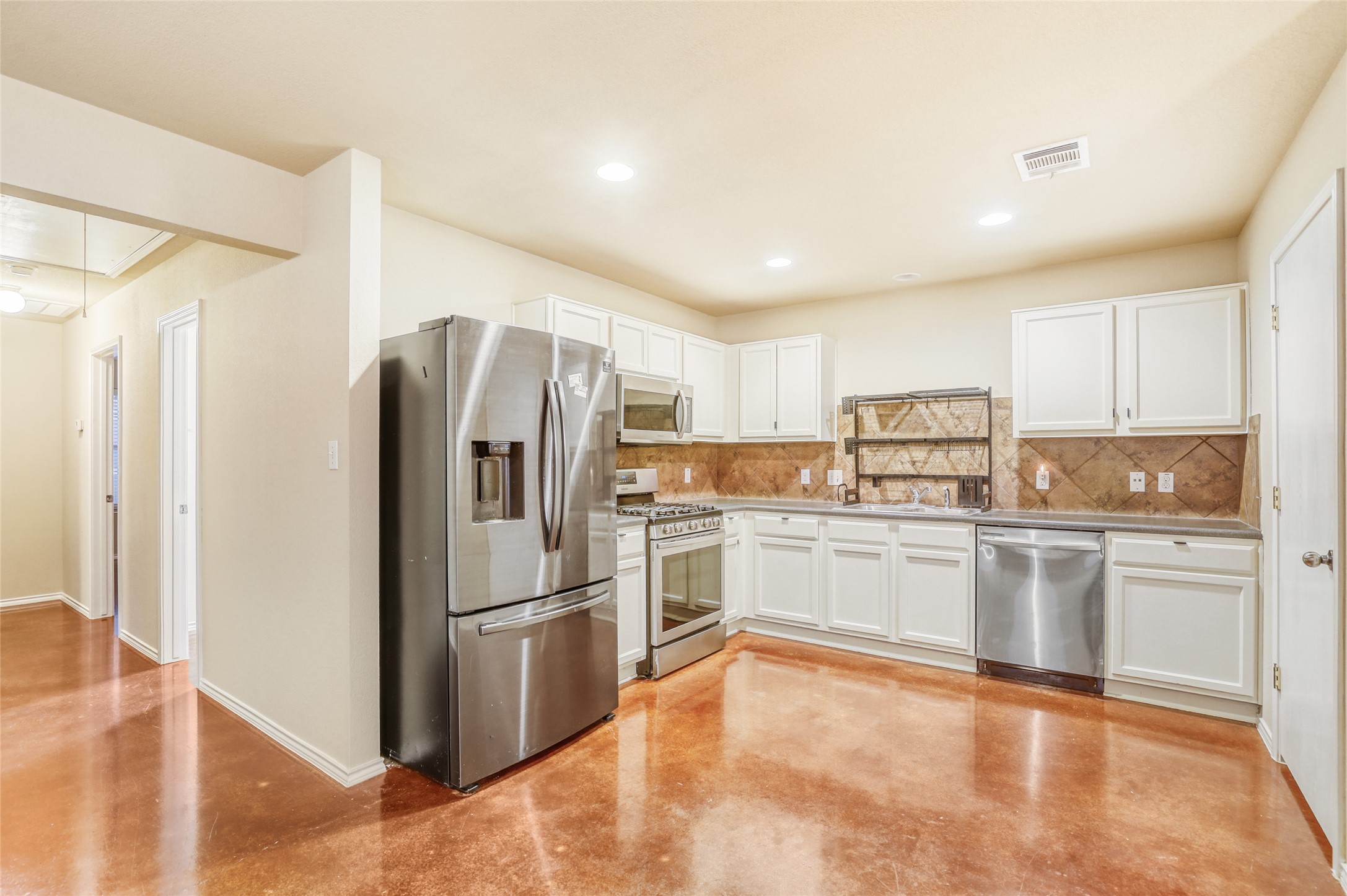 4620 Best Way Austin, TX 78725 - Photo 5 of 11 a kitchen with granite countertop stainless steel appliances a refrigerator and white cabinets
