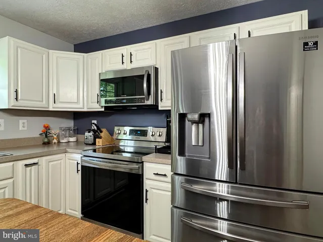 a spacious bedroom with a bed and a flat tv screen on dresser