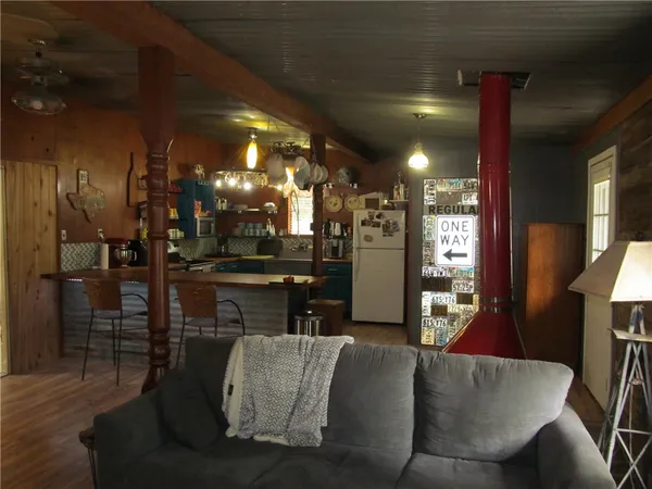 a living room with couches and kitchen view with wooden floor