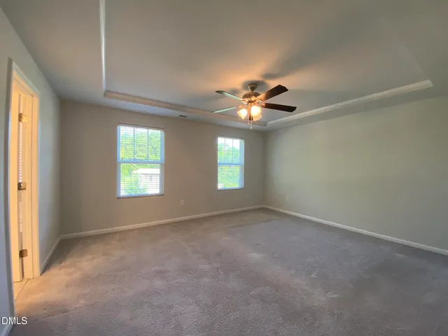 an empty room with chandelier fan and windows