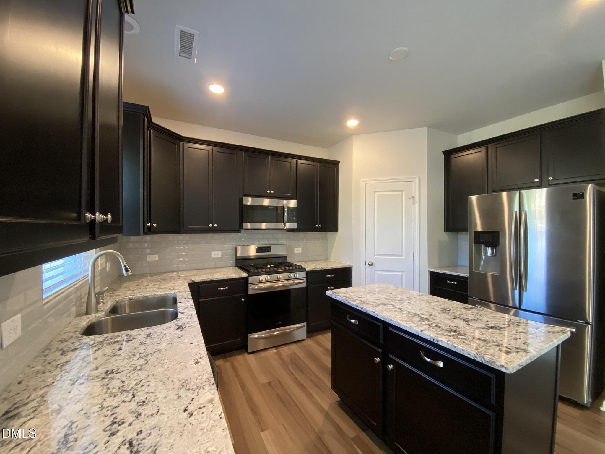 218 Loxton Street Fuquay-Varina, NC 27526 - Photo 8 of 37 a large kitchen with granite countertop stainless steel appliances and wooden cabinets