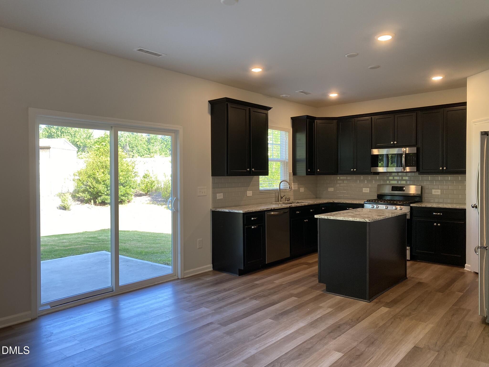 218 Loxton Street Fuquay-Varina, NC 27526 - Photo 10 of 37 a large kitchen with stainless steel appliances granite countertop a stove a sink and a microwave